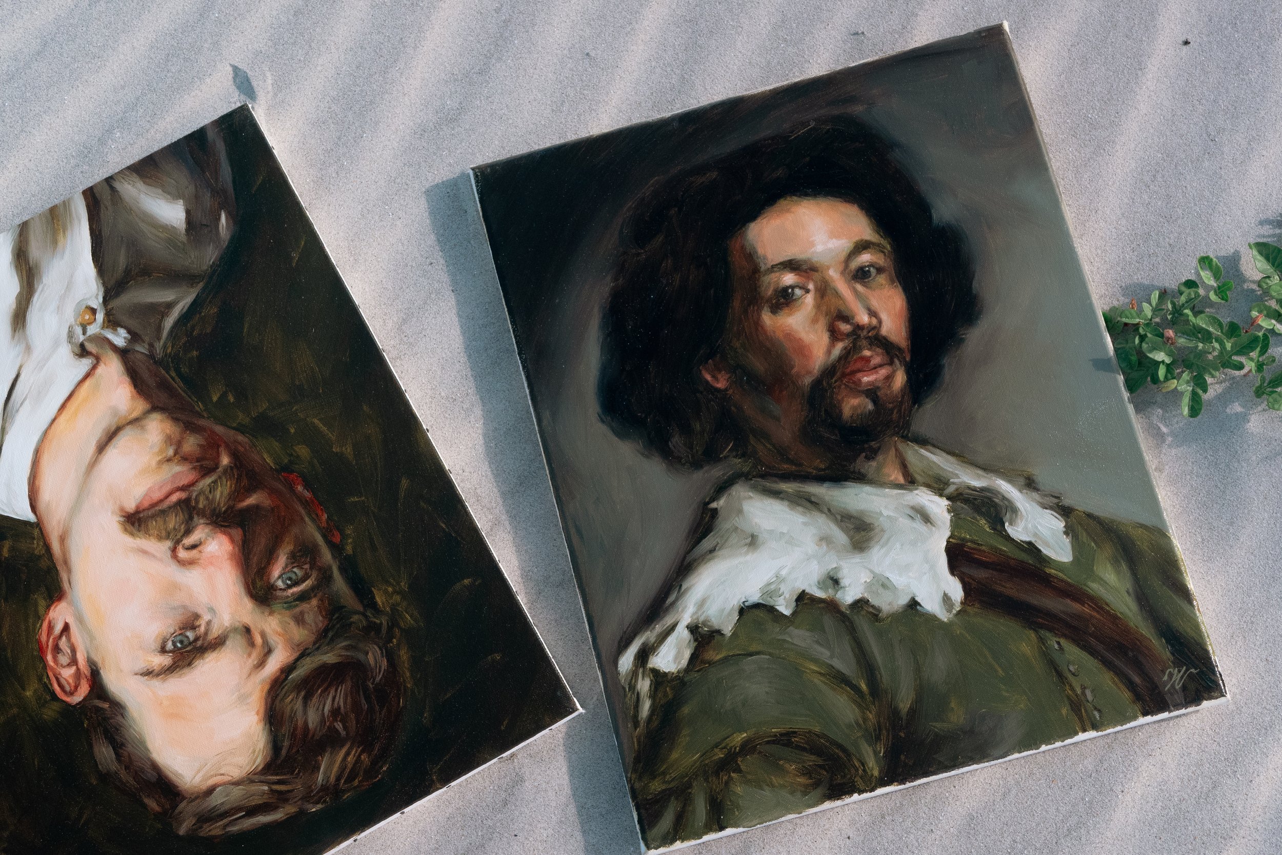 Two oil portrait paintings displayed on sand in Tybee Island coastal setting