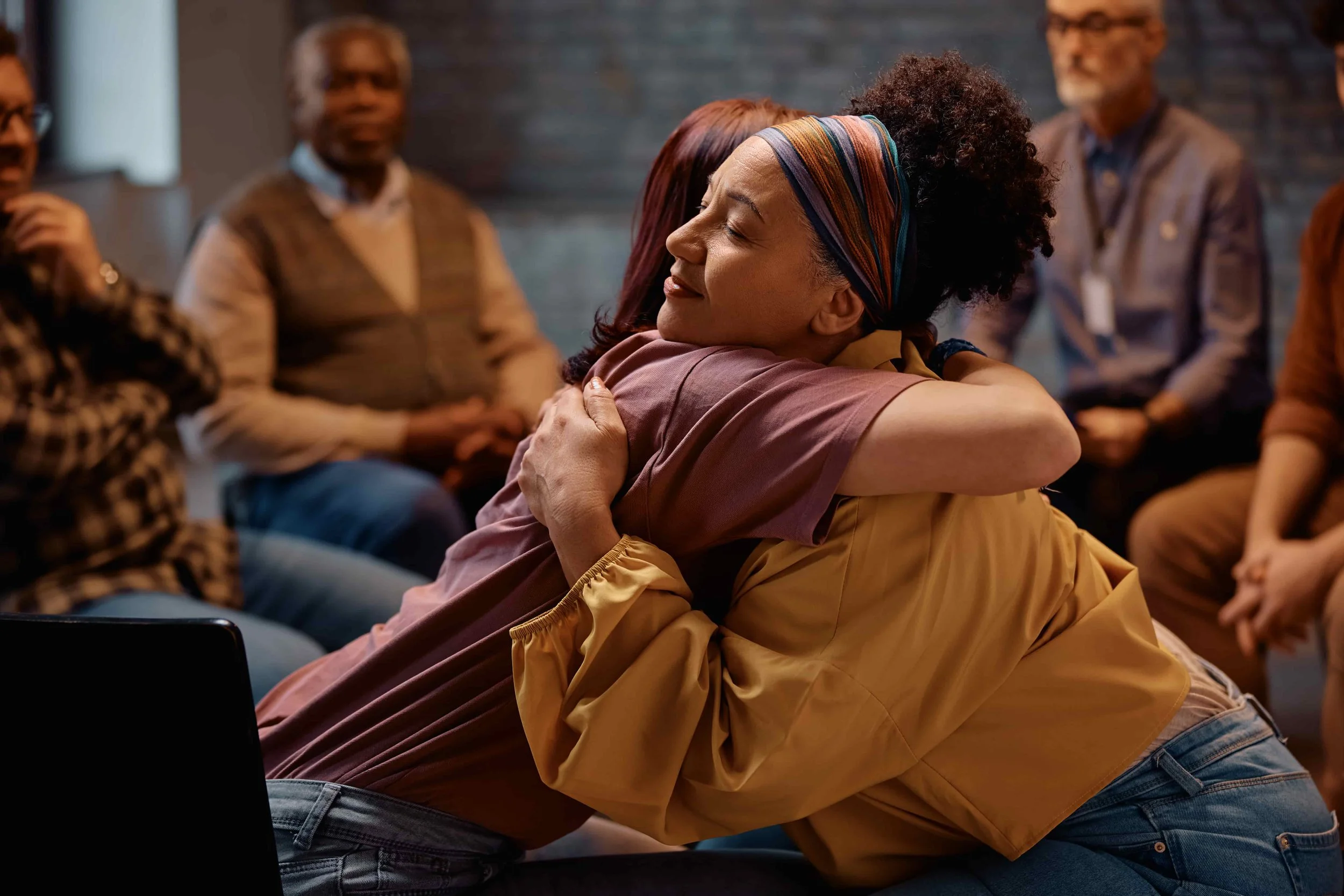 two women embracing at a group counseling session