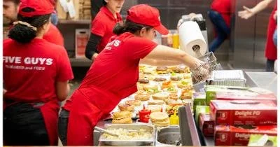 Workers making food at Five Guys restaurant.