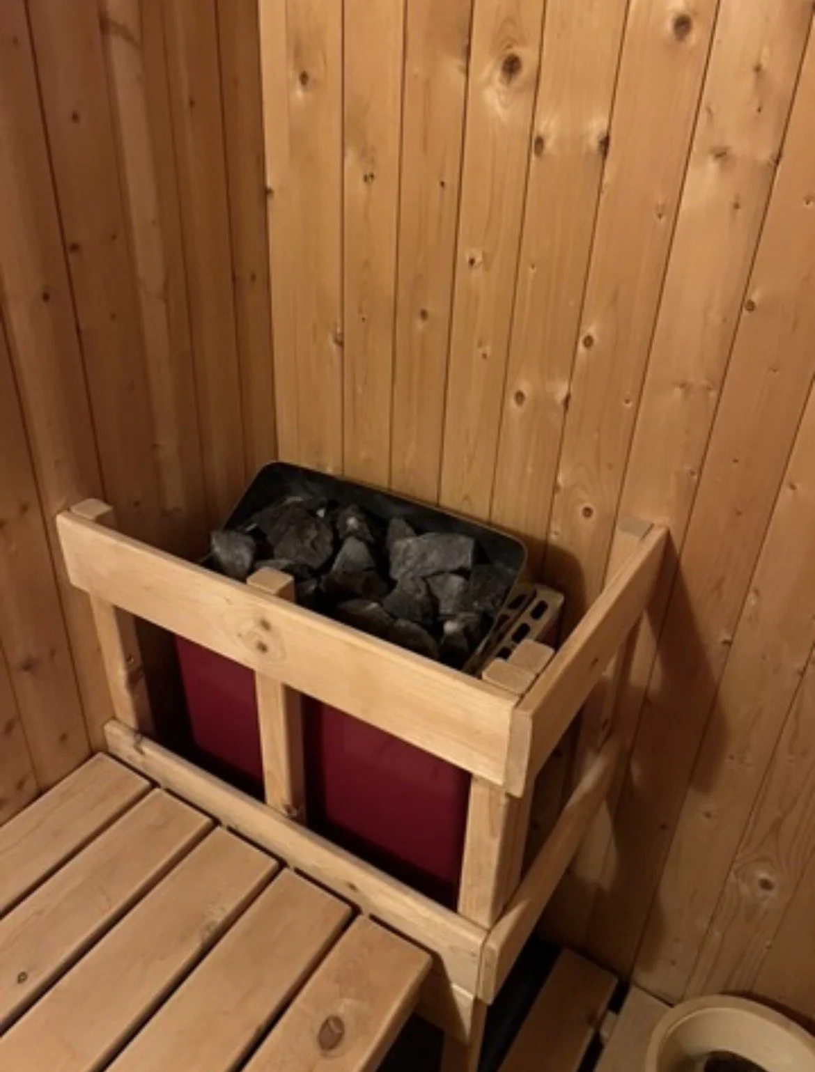 Wood-burning sauna heater filled with stones inside a wood-paneled sauna