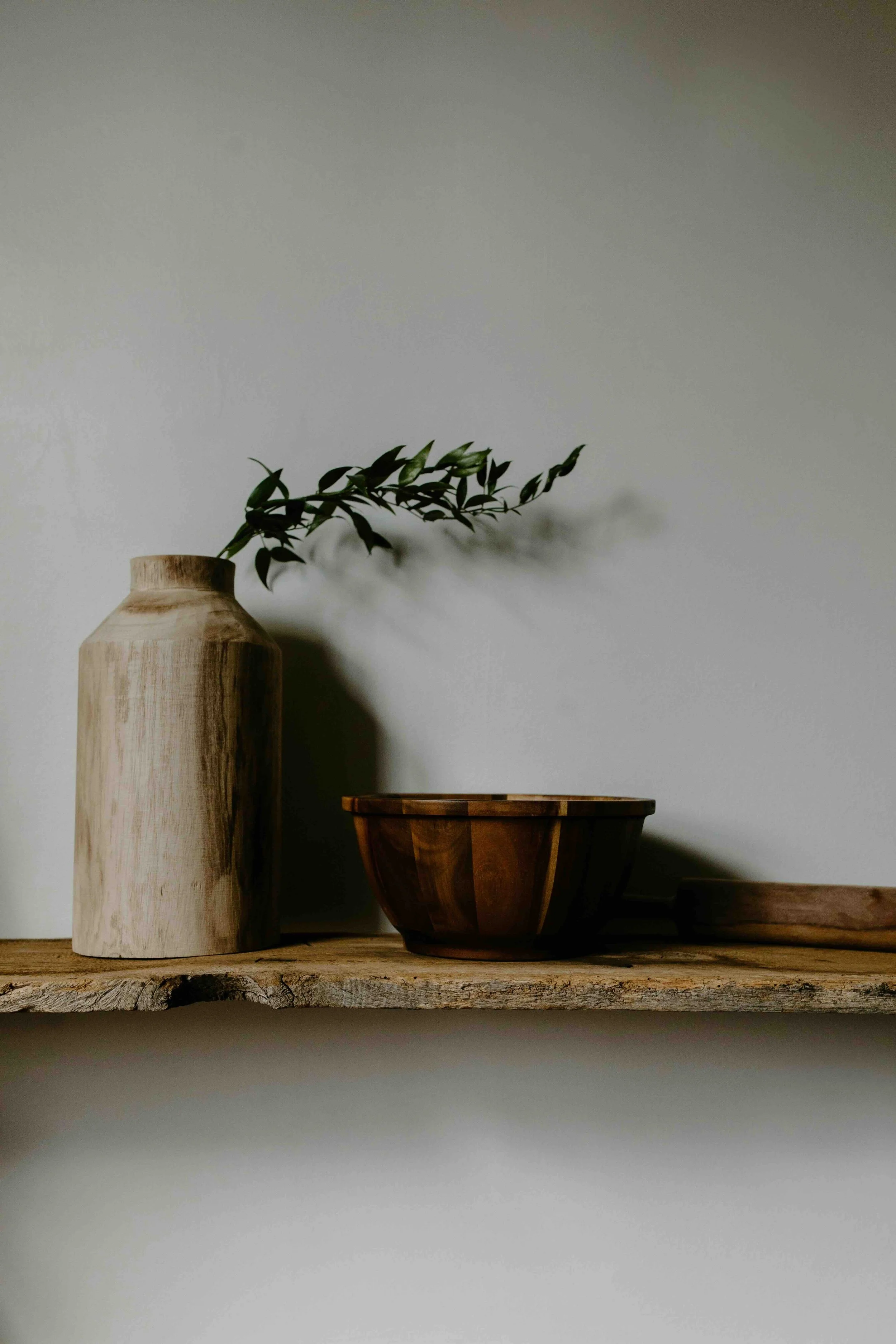 A wooden vase and bowl sitting on a shelf