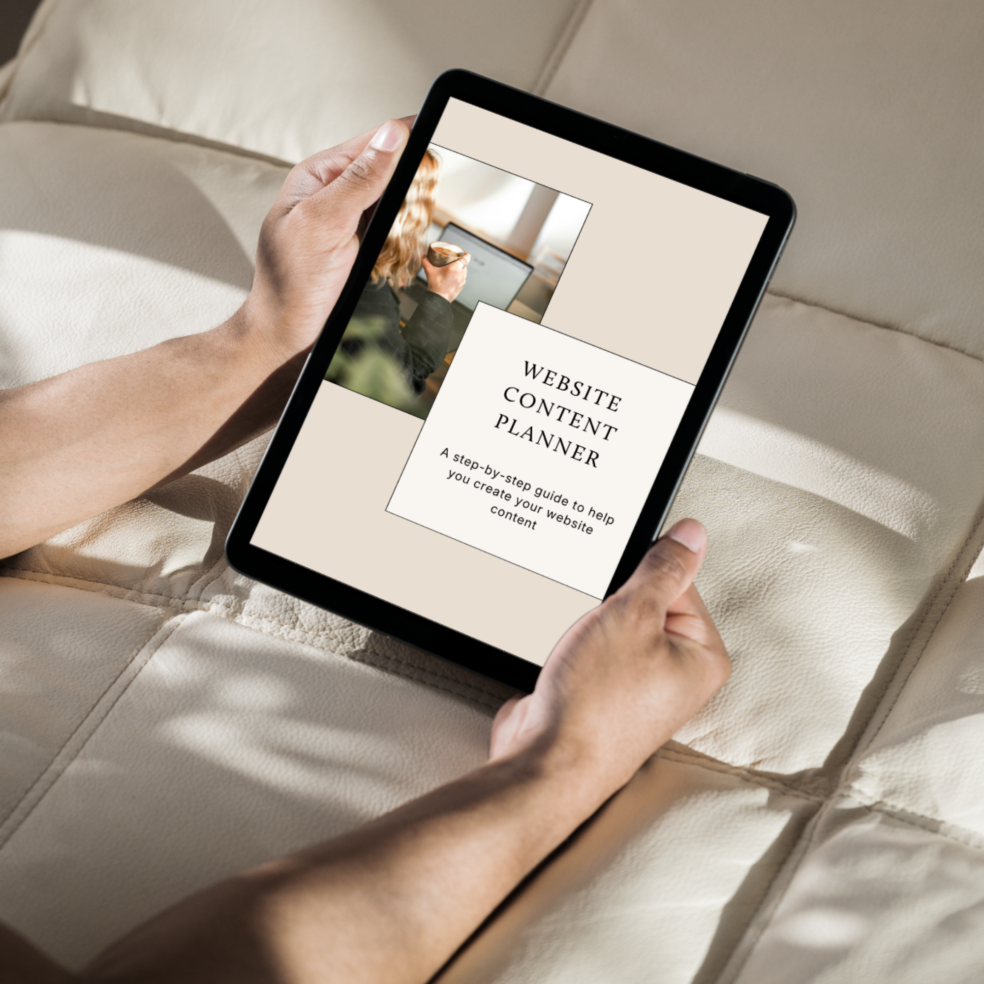 Person holding a tablet with a website content planning page visible on the screen, resting on a cream-colored fabric surface.