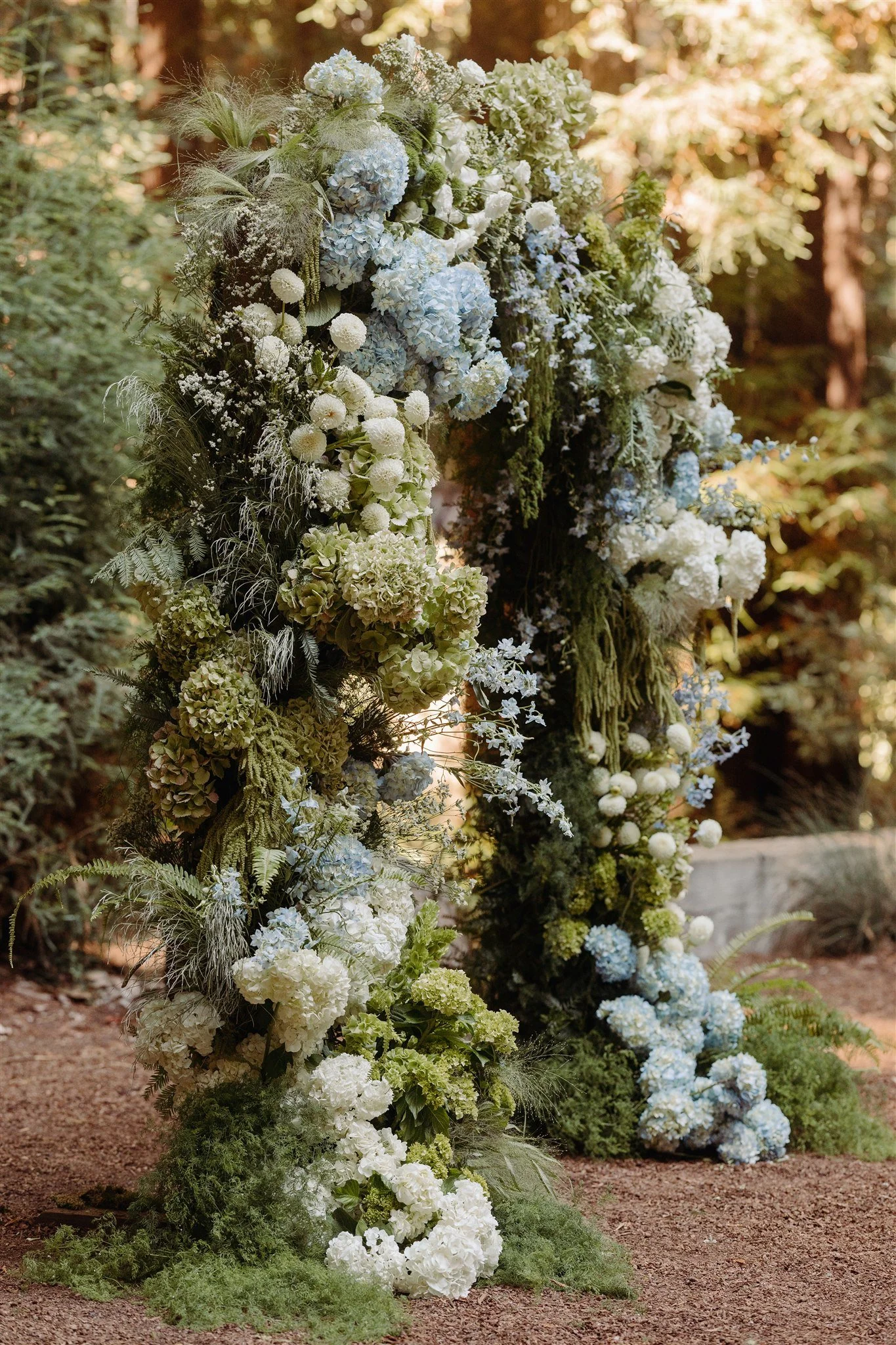 wedding arch with blue white and green flowers and moss