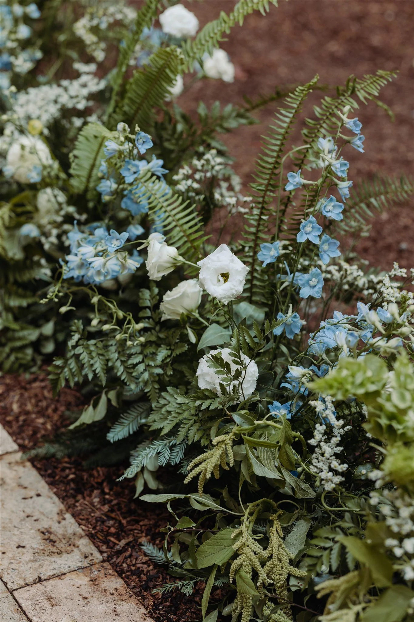 full wedding aisle with blue and white flowers and ferns