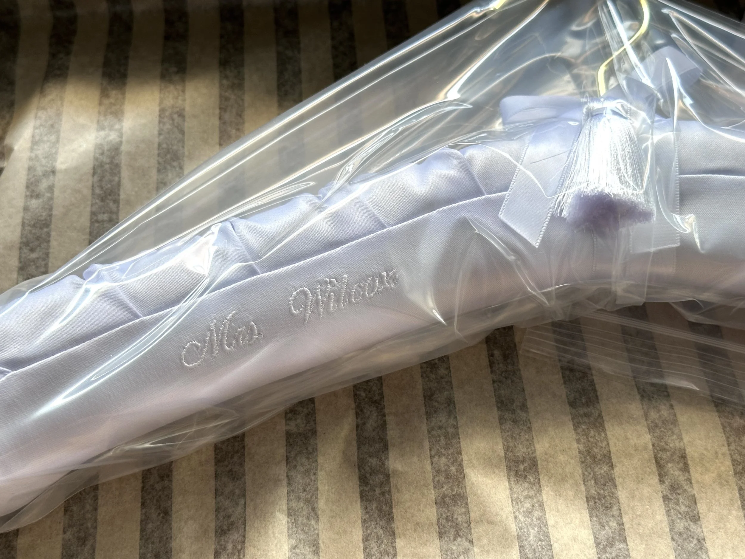 Adventure awaits custom embroidery on gray satin bridal hanger, wrapped in plastic, ready for delivery.