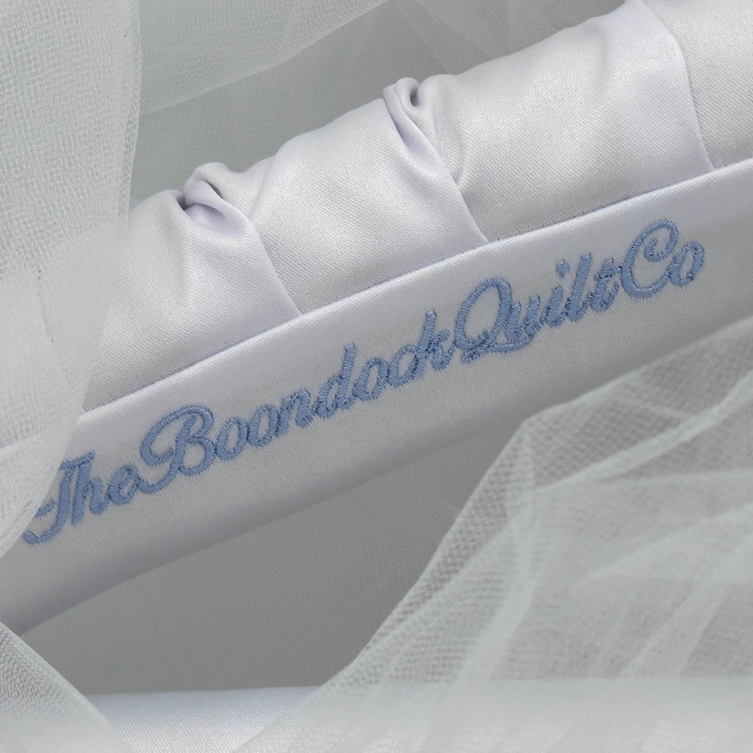Custom baby blue embroidery for the boondock quilt co custom bridal hanger.  Picture shows blue embroidery on white satin folds.