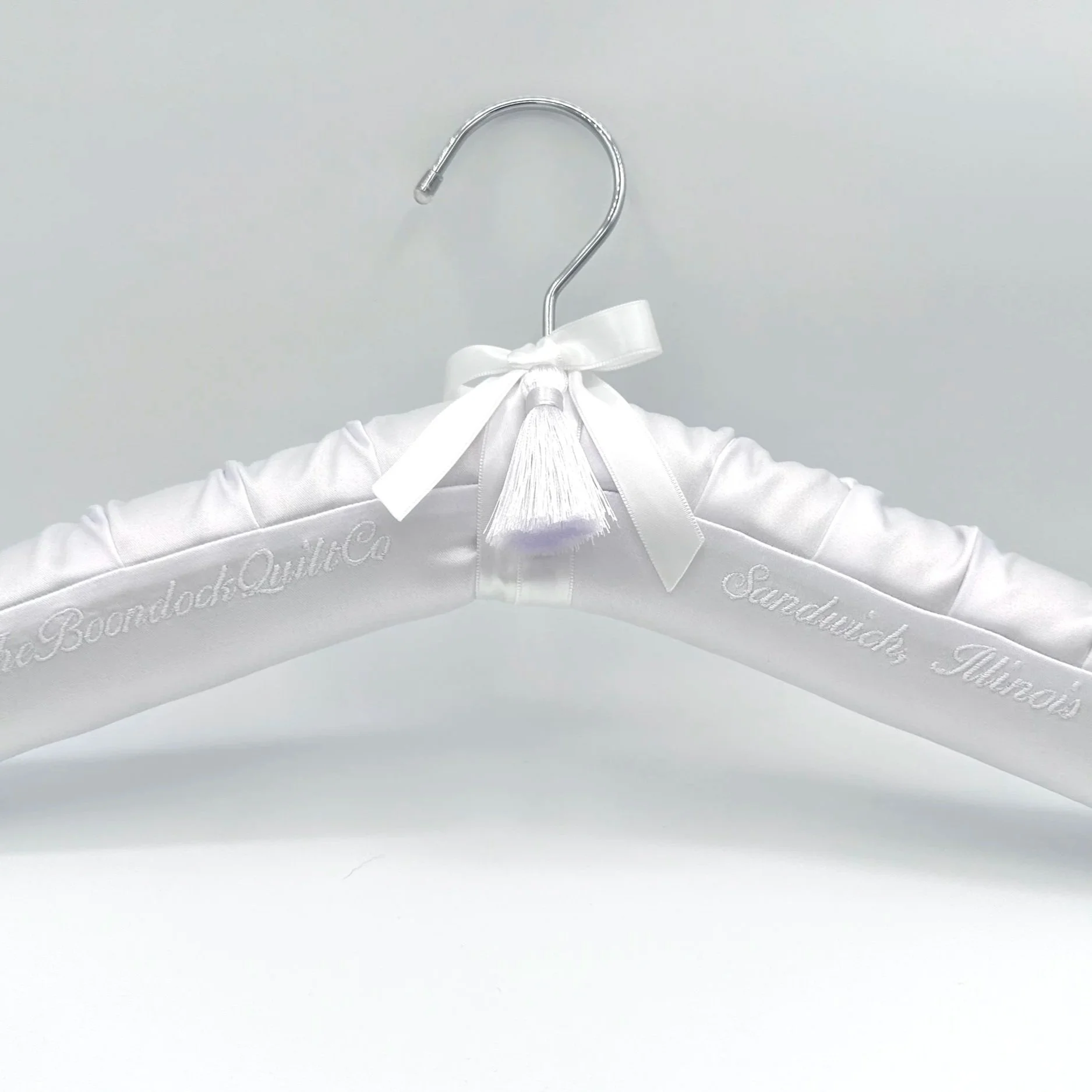 White satin bridal hanger with personalization.  White embroidery thread, tassel, ribbon and bow.