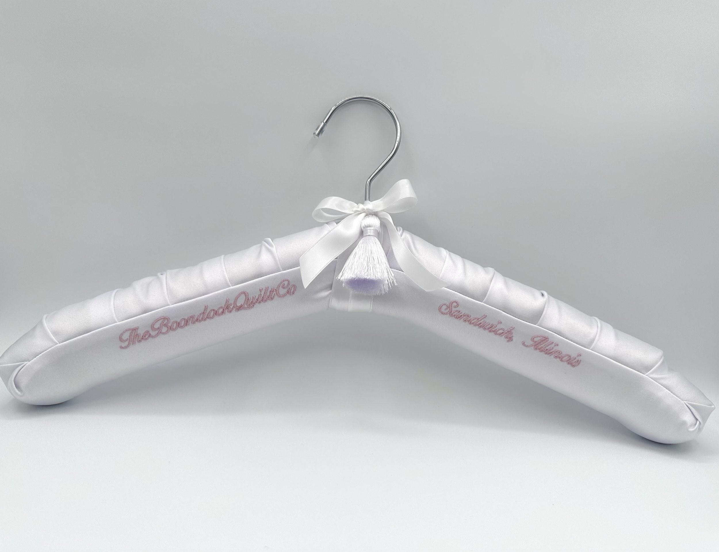 Luxe white satin wedding dress hanger on a gold hanger body with pink personalized embroidery. Completed with double faced satin ribbon and tassel.