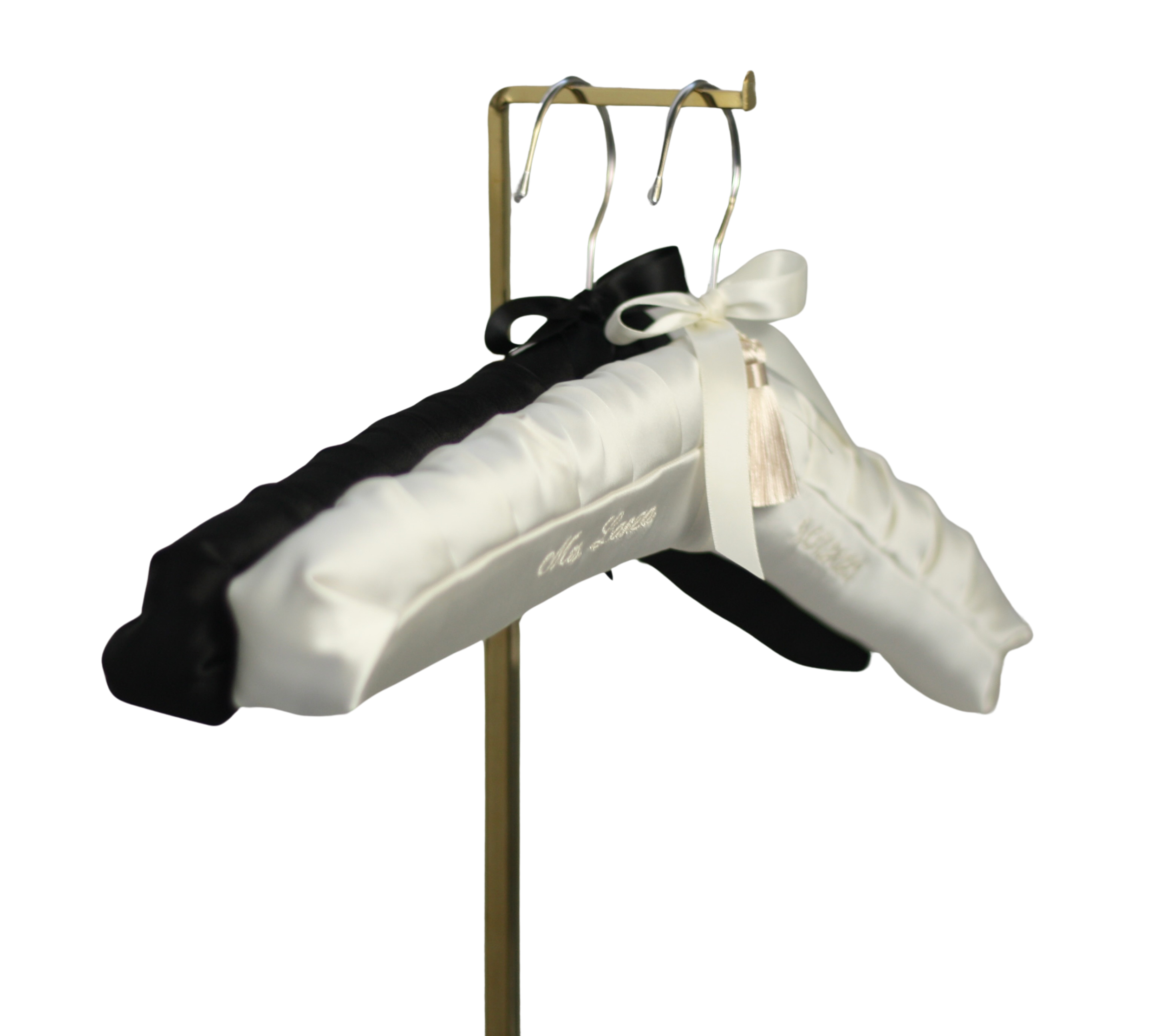 Two satin bridal pillows, one black and one white, with bows, displayed on a metal stand.