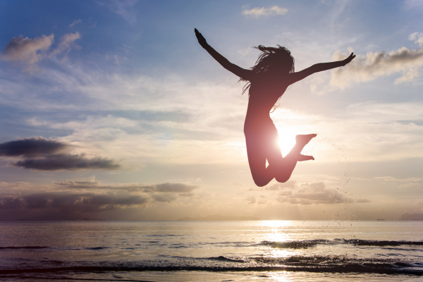 Person jumping on the beach during sunset