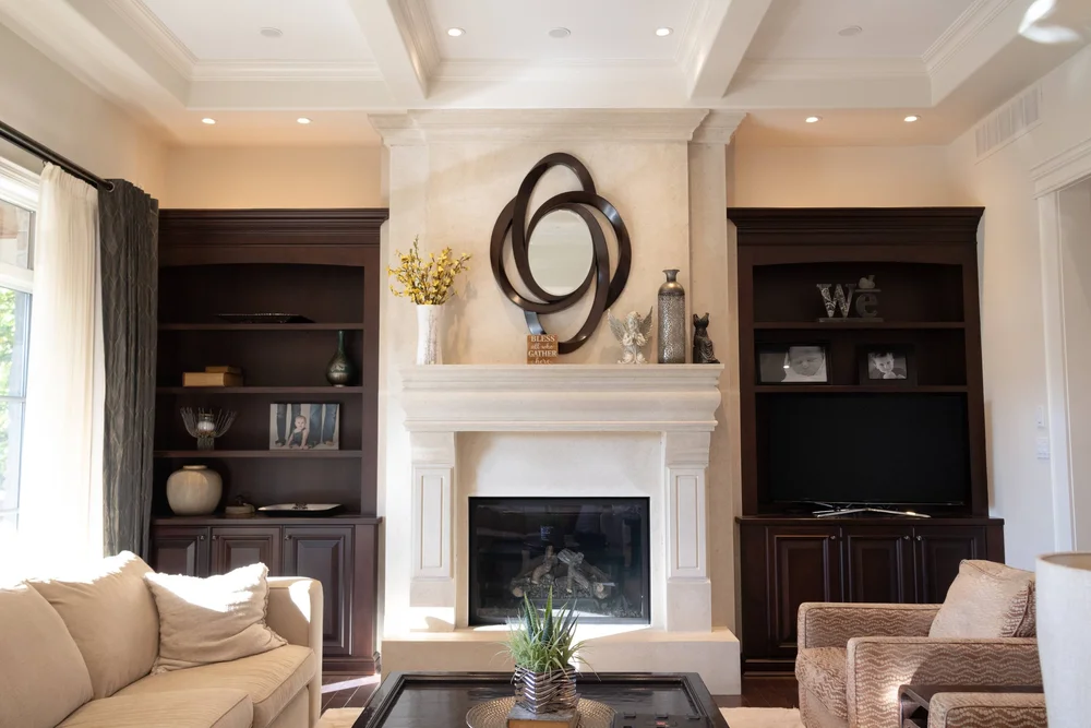 Finished living room with warm neutral walls, a white fireplace and dark built-in shelving, from McHugh Painting’s interior gallery.