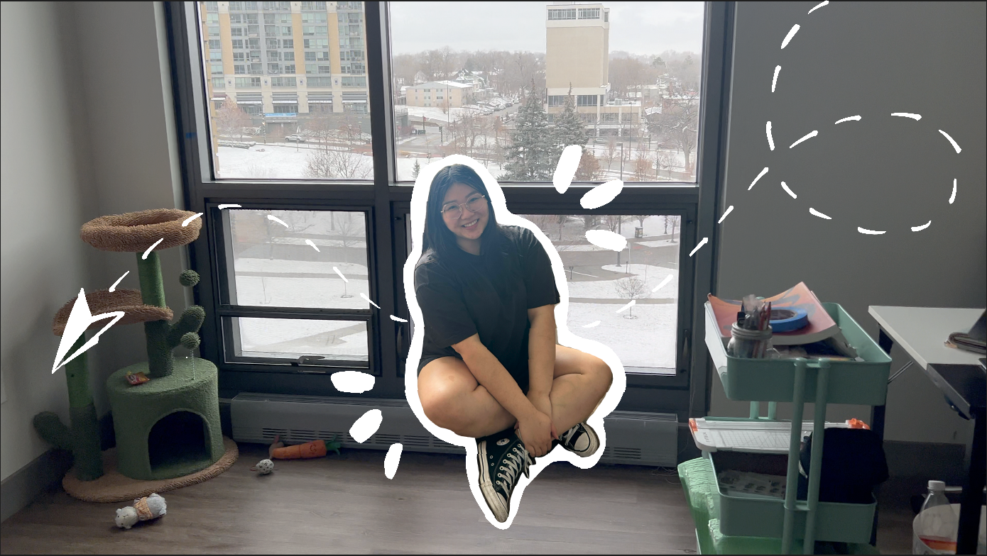 A woman sitting with her legs crossed on the floor near a window, meowing to a dog, with a cat tree, various toys, and office supplies in the room, and a cityscape with snow outside the window.