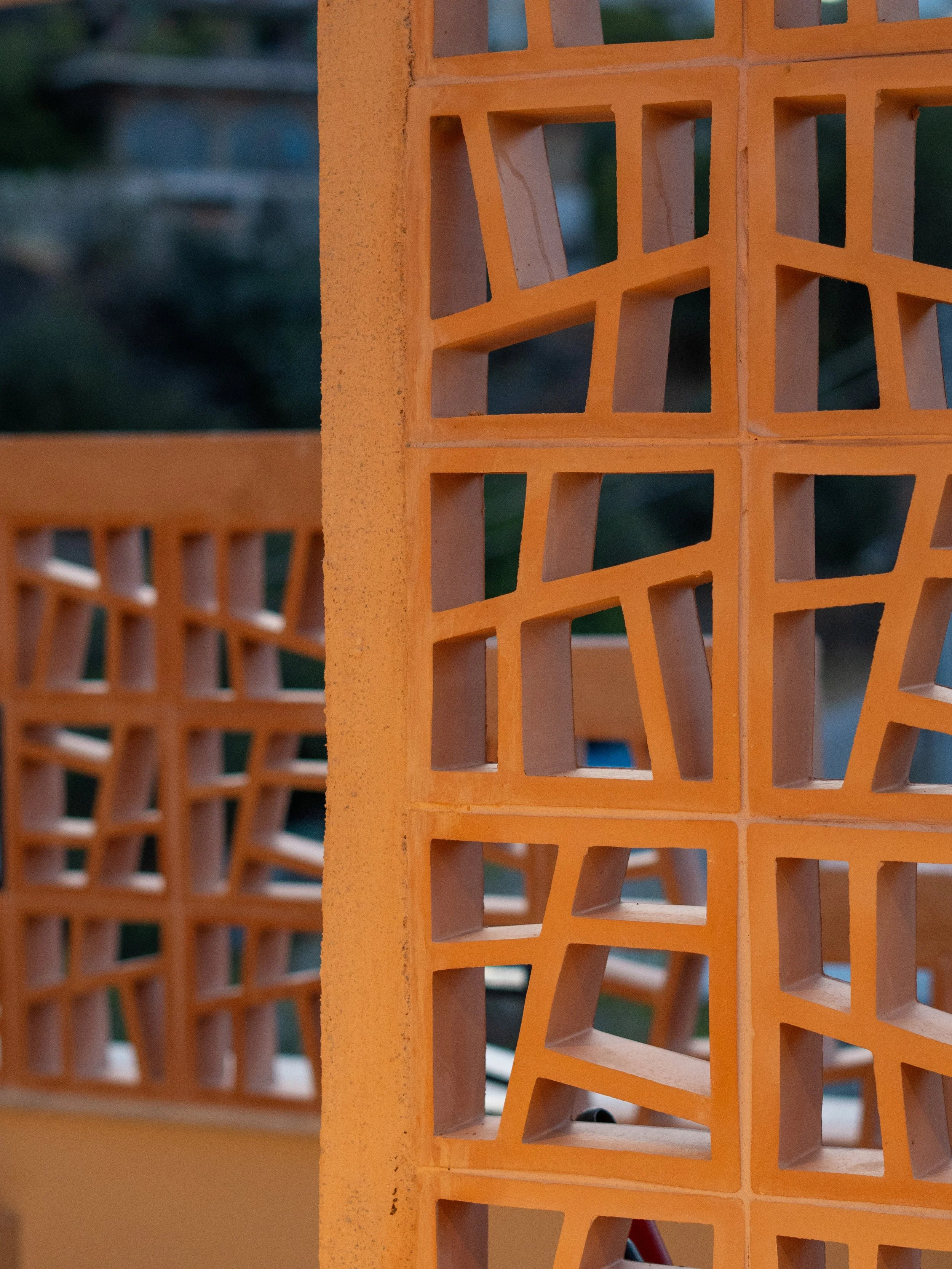Close-up of orange hollow bricks with rectangular openings, stacked vertically.