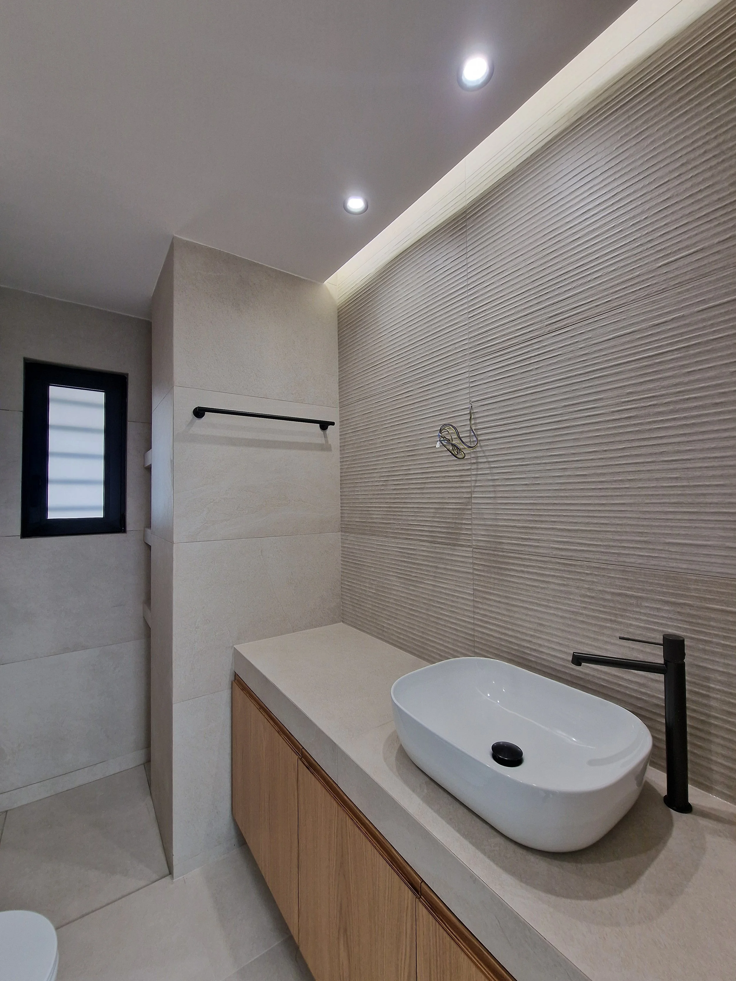 Modern bathroom with a vessel sink, black faucet, textured beige wall, and a small window.