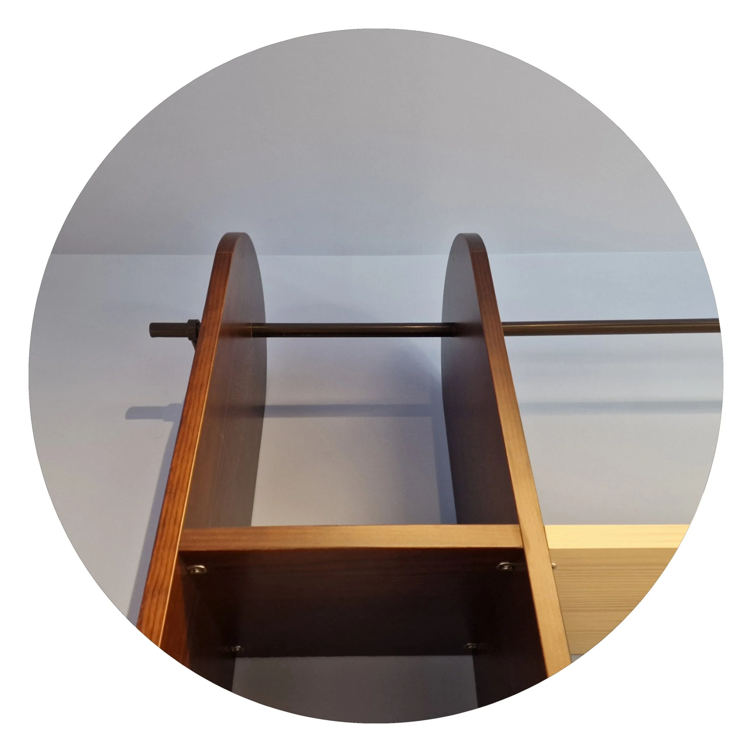 Part of a coat rack with wooden supports against a white wall.