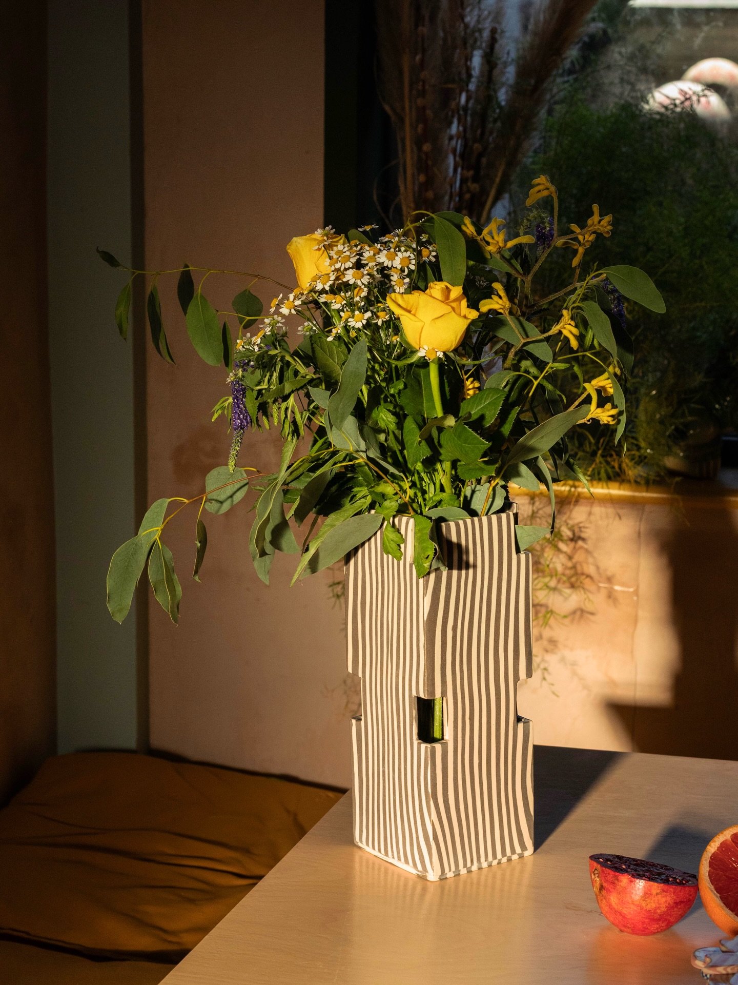 Brown striped vase in spring. Pictured in @jetsammade perfect sun trap kitchen 🤎 I enjoy how the symmetrical holes in this design allow a lil sneak at the stems and also a definitive water line for your flowers.
