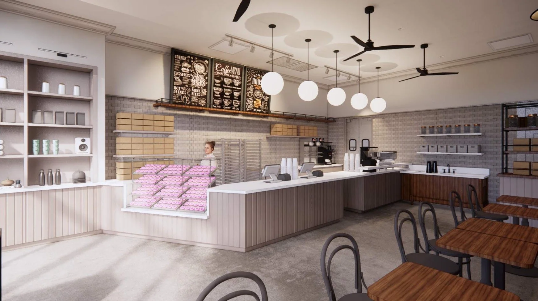 Inside a coffee shop with a stainless steel La Marzocco espresso machine, two employees, shelves with coffee supplies, and condiment bottles on the counter.