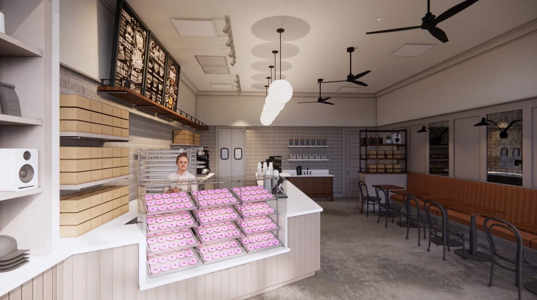 Interior of a restaurant with beige padded bench seating, black chairs, wooden tables, and a wall-mounted light fixture.