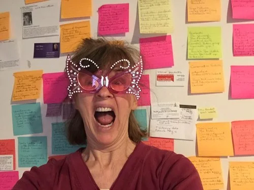 Susan Isaac in her office standing in front of a wall of clutter