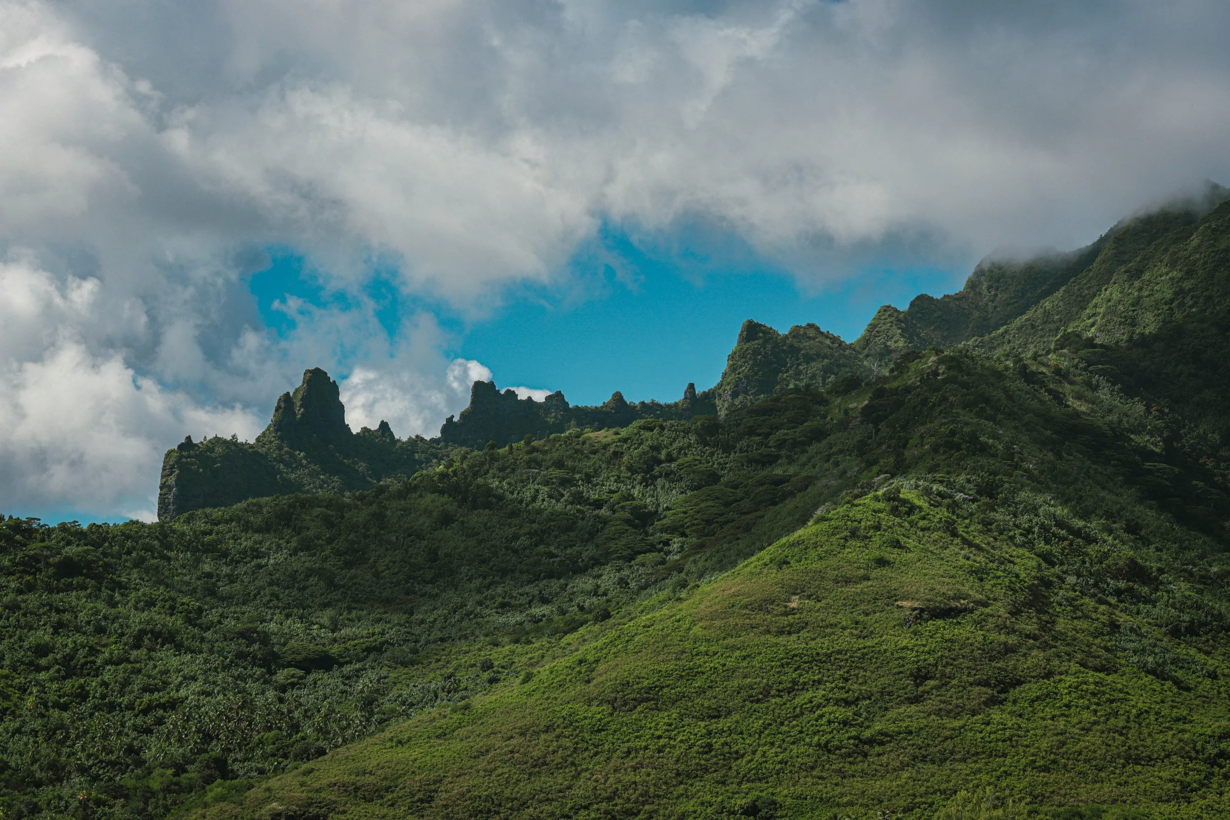 Lush green mountains under a partly cloudy sky with patches of blue.