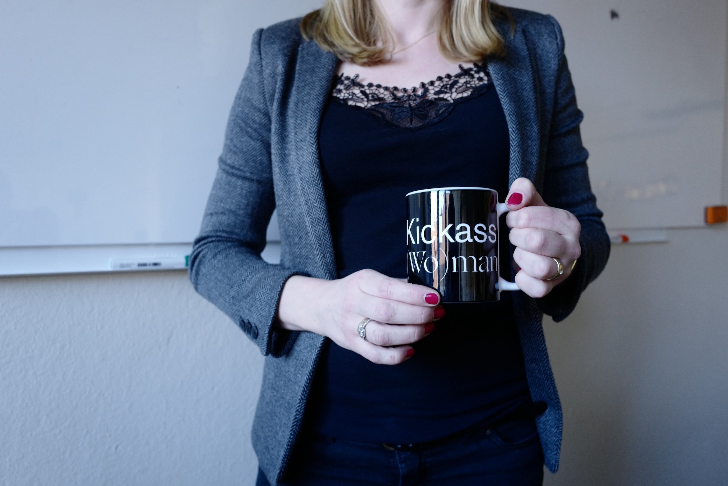 Woman holding a mug with the words 'Kickass Woman' in an office setting.