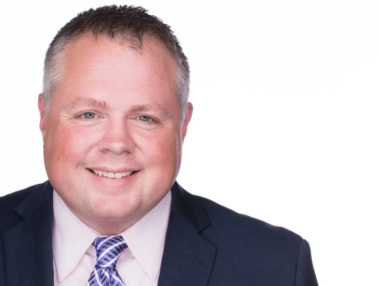 Chaz Cirame in a suit and tie on a white background.