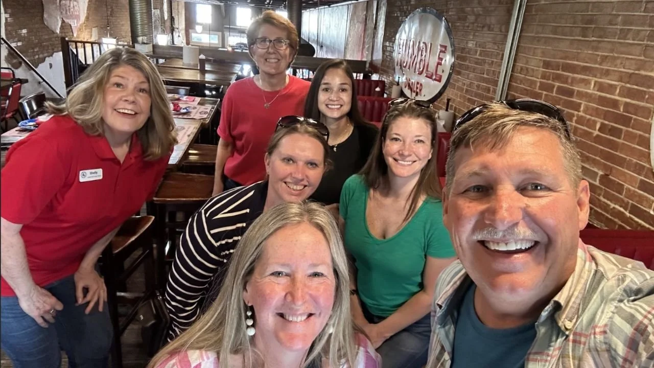 Friends smiling together for a group selfie inside a restaurant