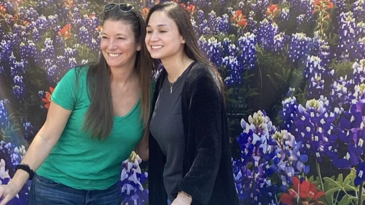 Two women posing in front of colorful flower mural backdrop