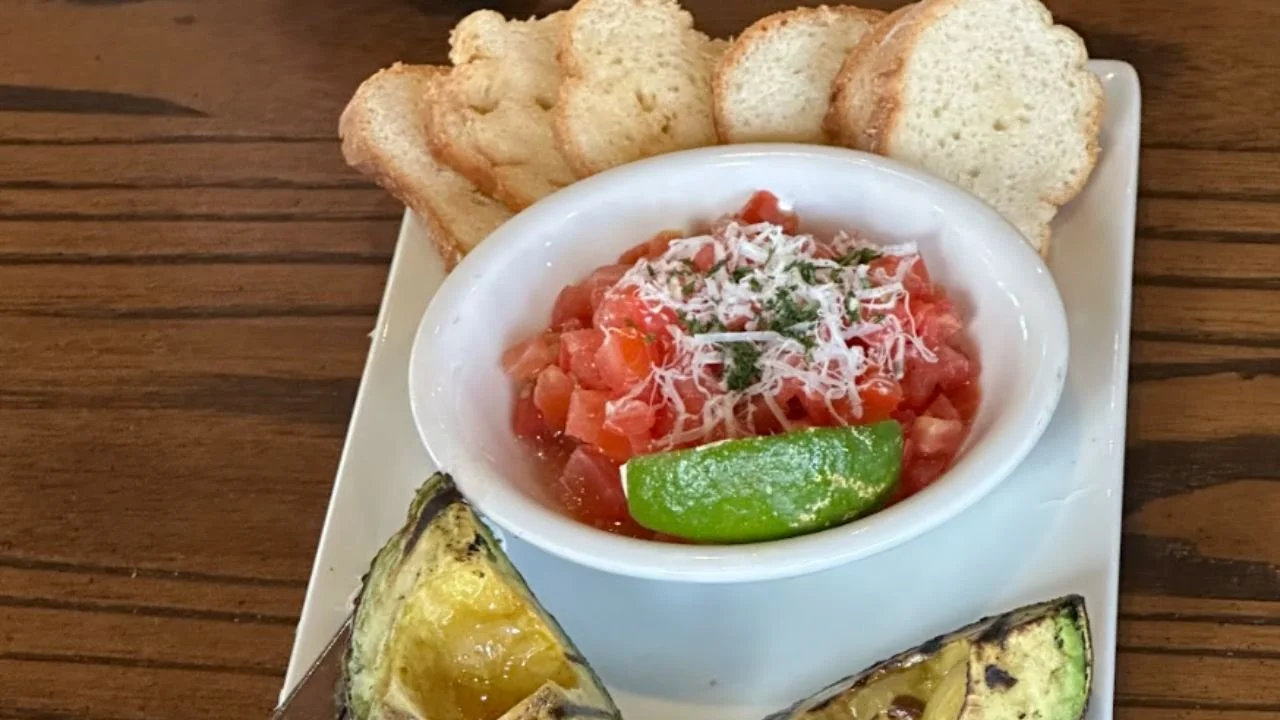 Restaurant appetizer with roasted avocado and tomato topping with bread slices on a food tour with Lone Star Food Tours