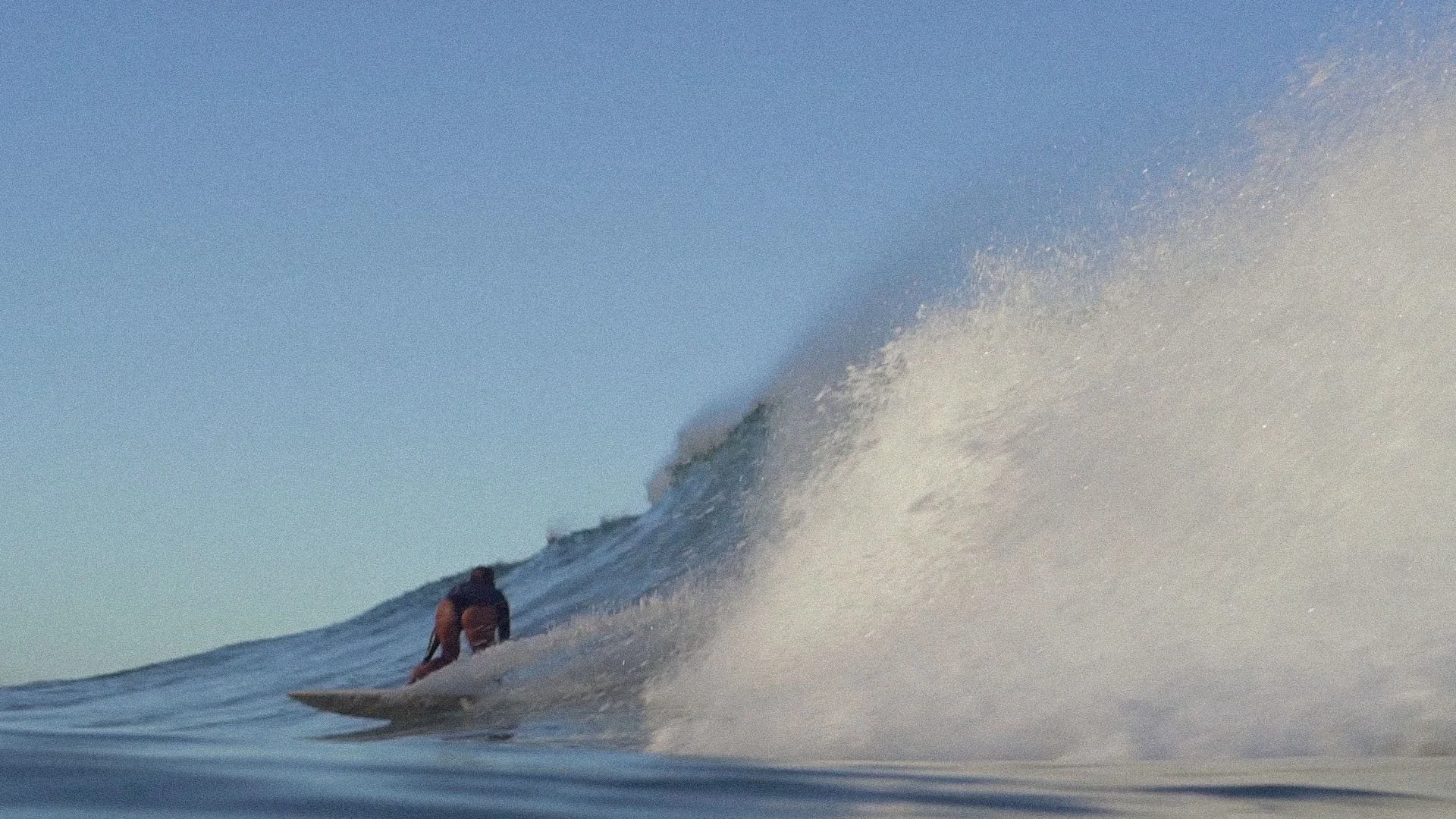 Surfer riding a wave in the ocean during daylight.