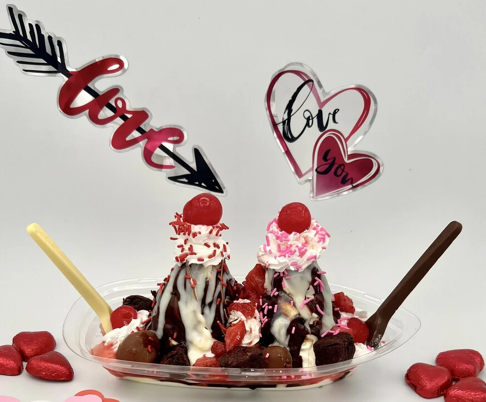 Lover&rsquo;s Boat sundae for two with twin peaks of soft-serve, hot fudge, white chocolate, cherries, strawberries, brownies and white and milk chocolate spoons, with Love picks and red foil hearts, at Merla-Mae Ice Cream in London, Ontario