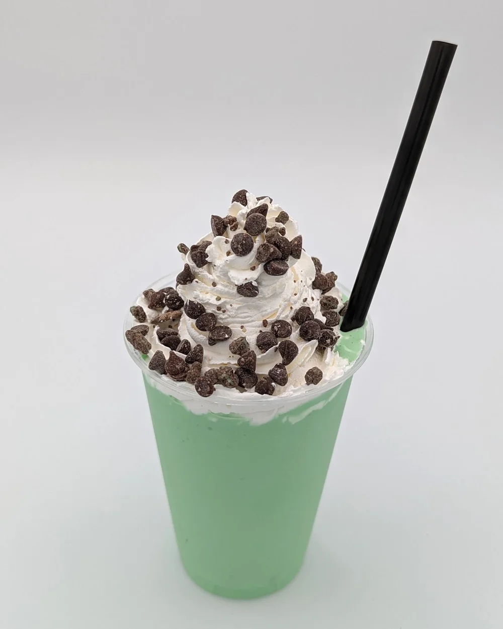 Mint-green shake topped with whipped cream and chocolate chips, with a black straw, at Merla-Mae Ice Cream in London, Ontario