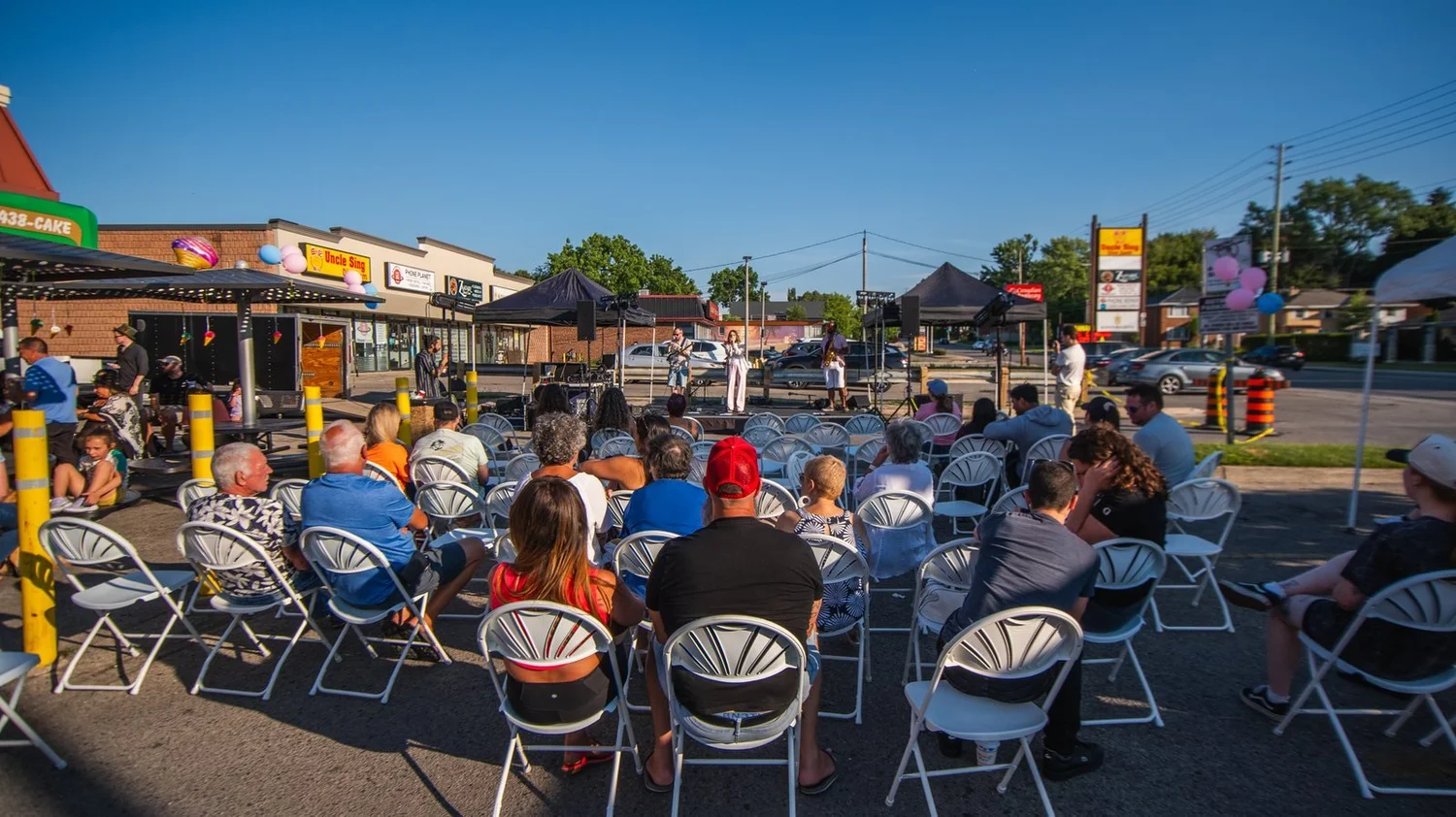 Rows of guests in folding chairs watching an afternoon set at National Ice Cream Day 2025, Merla-Mae Ice Cream in London, Ontario