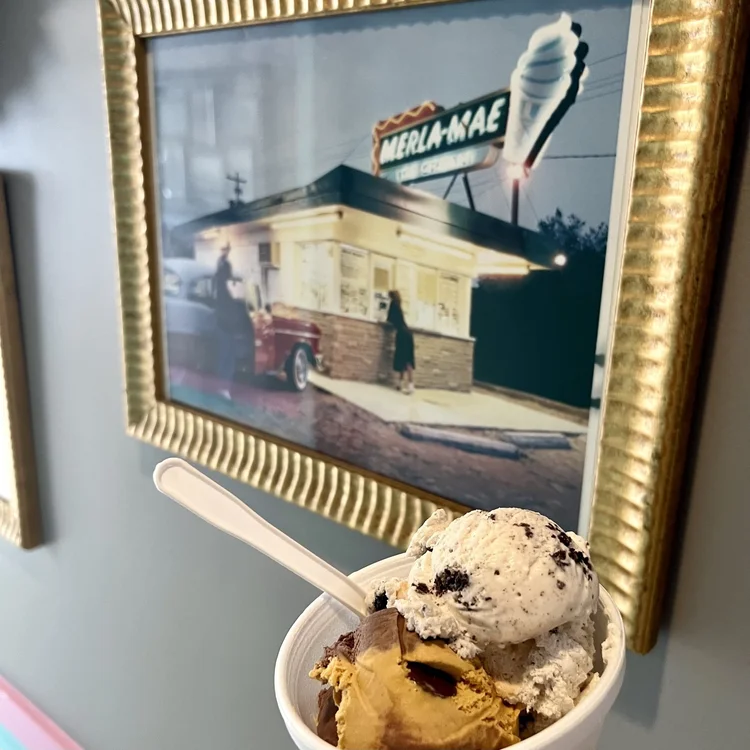 Cup of hard scoop ice cream in front of a framed vintage photo of the Merla-Mae ice cream stand, Merla-Mae Ice Cream in London, Ontario
