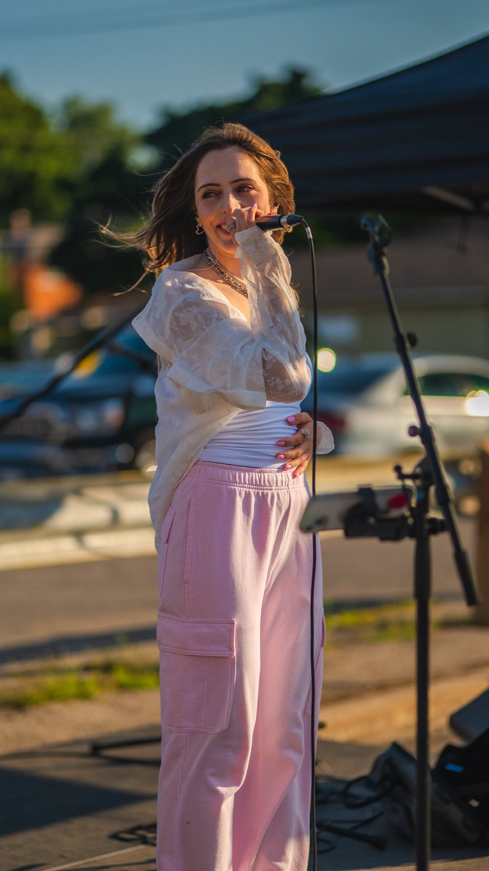 Lyubov Kay smiling as she sings into the microphone at National Ice Cream Day 2025, Merla-Mae Ice Cream in London, Ontario