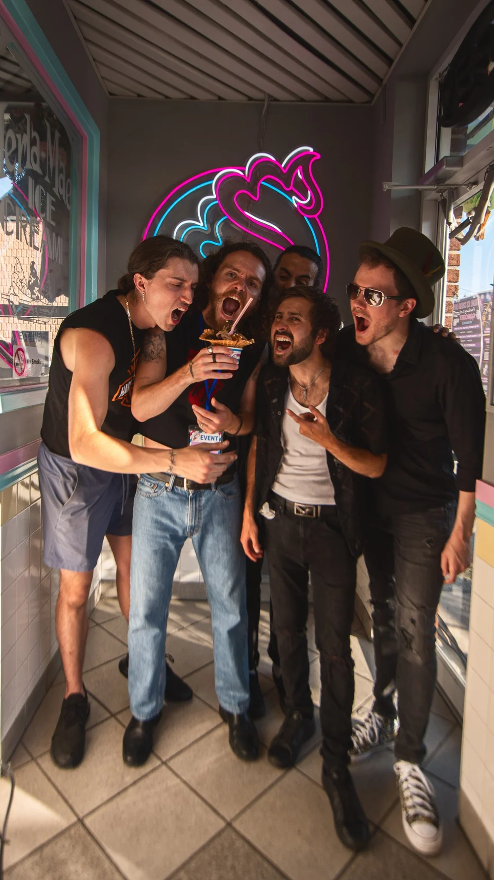 Tyrone Traher and The Rottweilers hamming it up with a sundae under the neon cone sign at Merla-Mae Ice Cream in London, Ontario