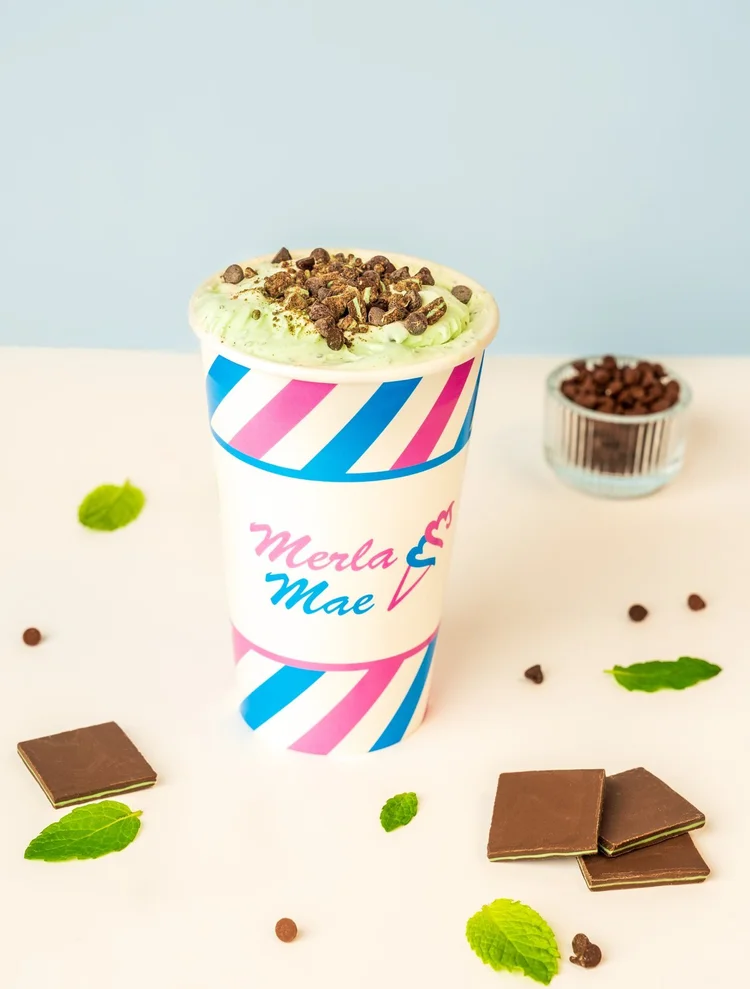 Mint-green Cream Shake Flurry topped with chocolate pieces in a pink and blue striped cup at Merla-Mae Ice Cream in London, Ontario