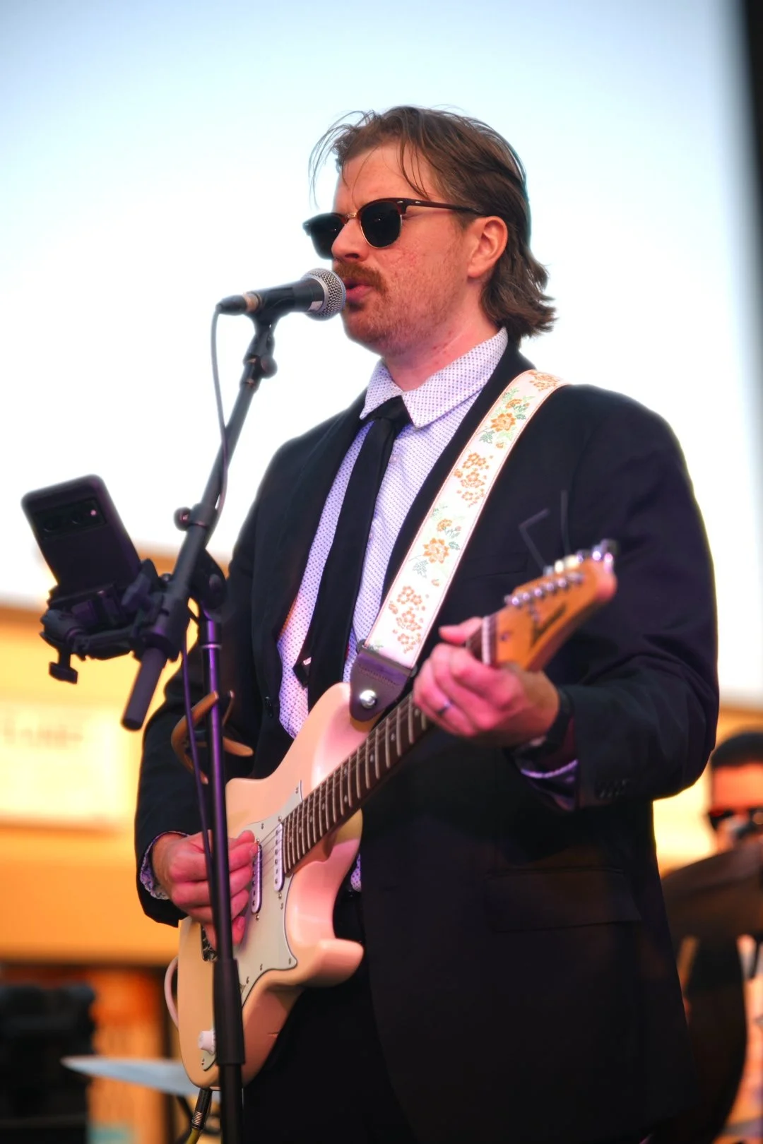 Turning Corners' guitarist in suit and sunglasses at National Ice Cream Day 2026, Merla-Mae