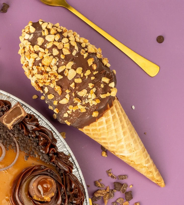 Chocolate-dipped ice cream drumstick rolled in chopped nuts on a purple table at Merla-Mae Ice Cream in London, Ontario