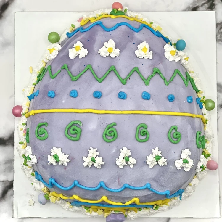Lavender egg-shaped ice cream cake decorated with piped zigzags, swirls, dots, white flowers and candy eggs, at Merla-Mae Ice Cream in London, Ontario