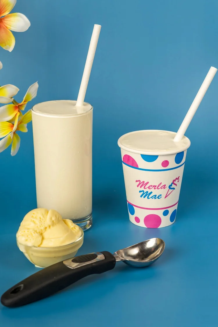 Vanilla milkshake in a tall glass and a polka-dot cup beside a scoop of vanilla ice cream at Merla-Mae Ice Cream in London, Ontario