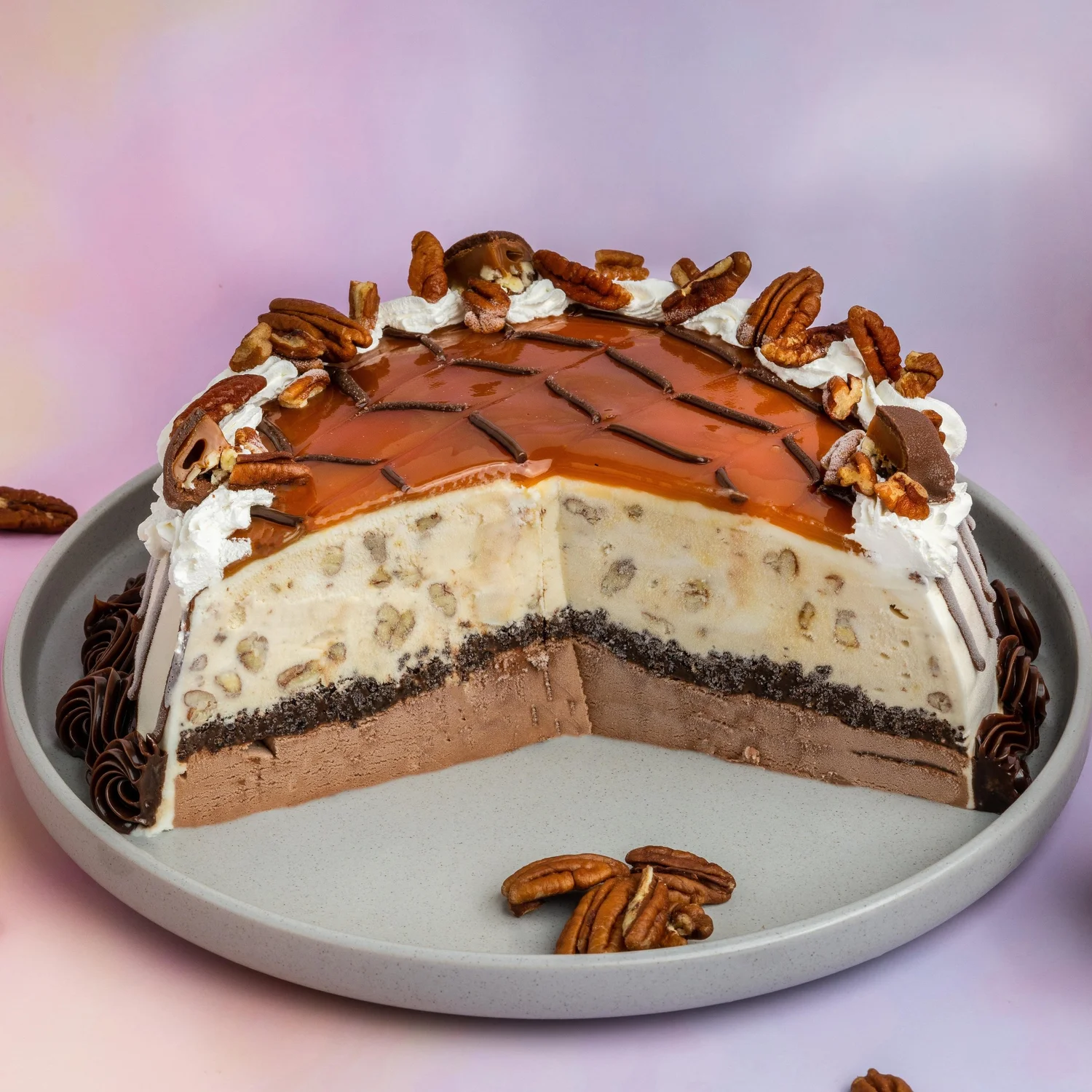 Turtle ice cream cake cut open to show a chocolate ice cream base, a cookie crunch layer and vanilla ice cream with pecans, topped with caramel, pecans and whipped cream, at Merla-Mae Ice Cream in London, Ontario