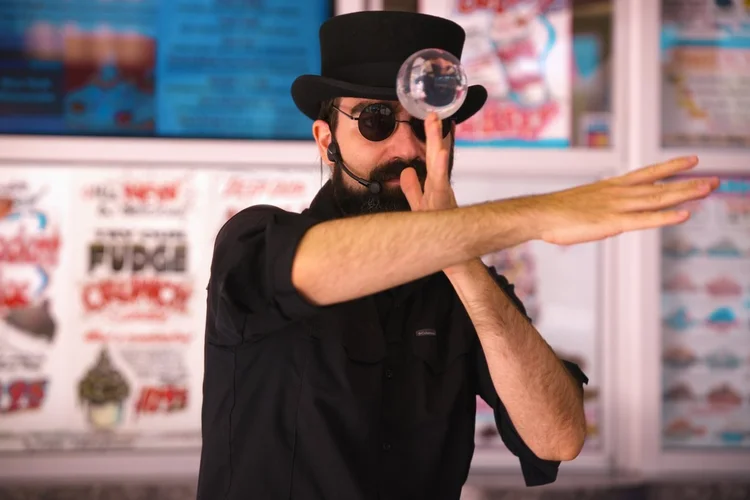 Magician rolling a crystal ball in front of the menu boards at Merla-Mae Ice Cream in London, Ontario
