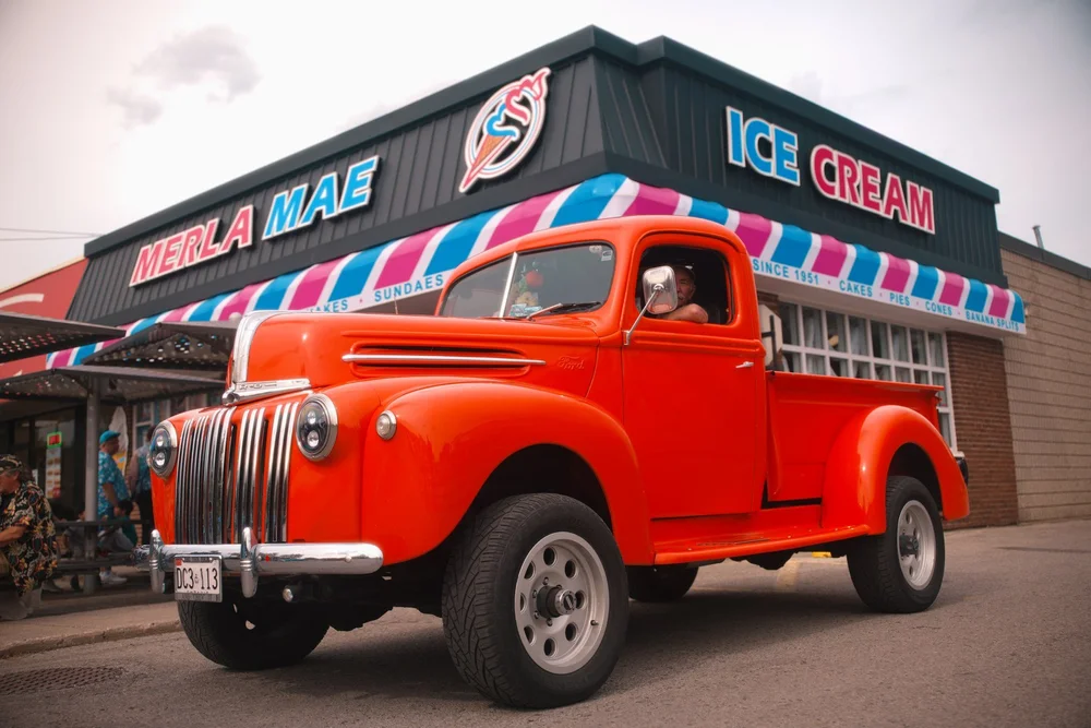 Vintage red pickup truck parked outside Merla-Mae Ice Cream at the annual car show