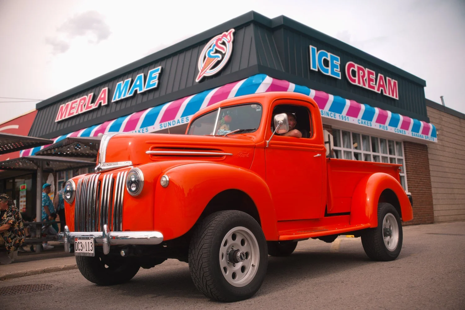 Vintage red pickup truck parked outside Merla-Mae Ice Cream at the annual car show