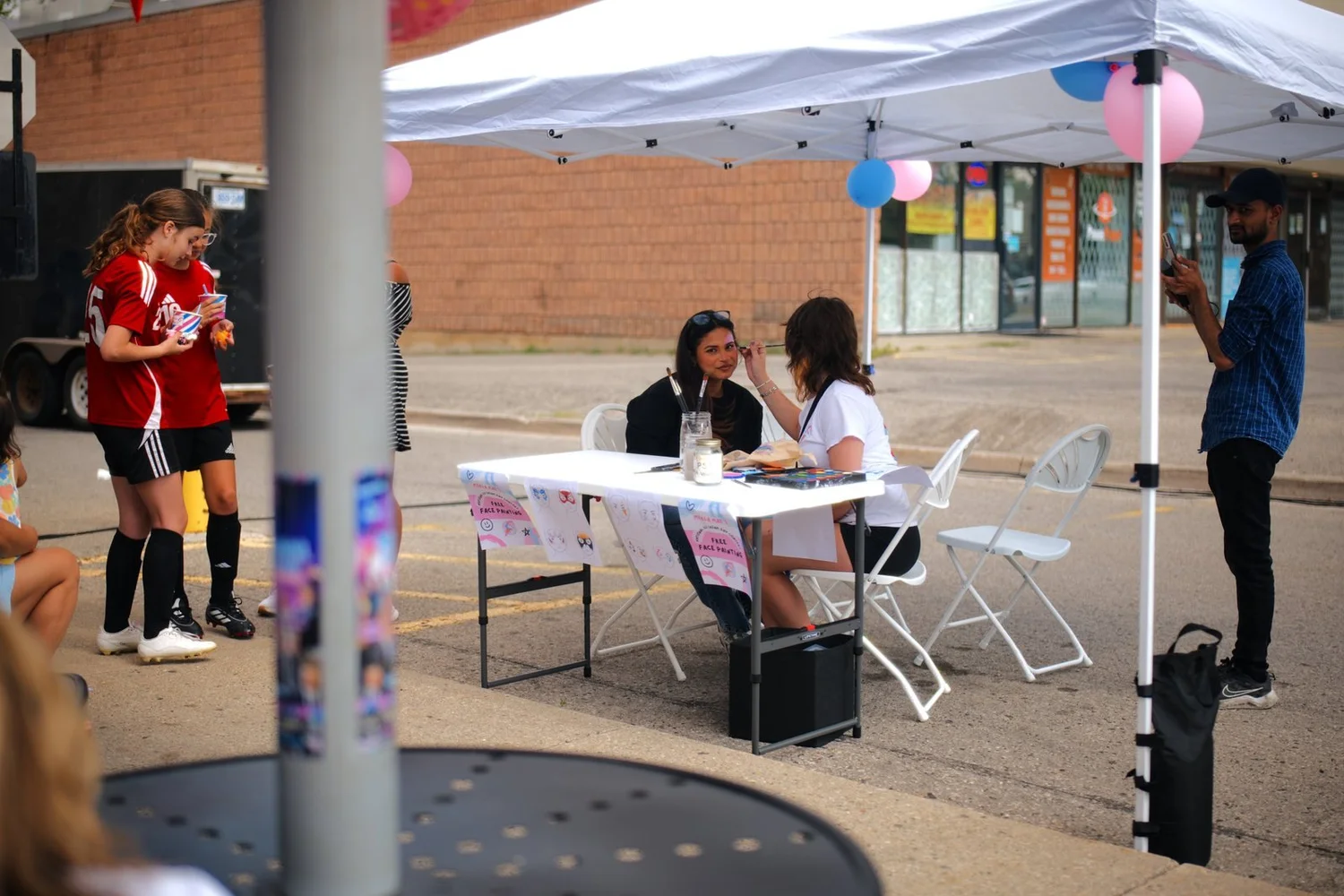 Free face-painting station under a tent in the Merla-Mae parking lot at National Ice Cream Day 2026 in London, Ontario