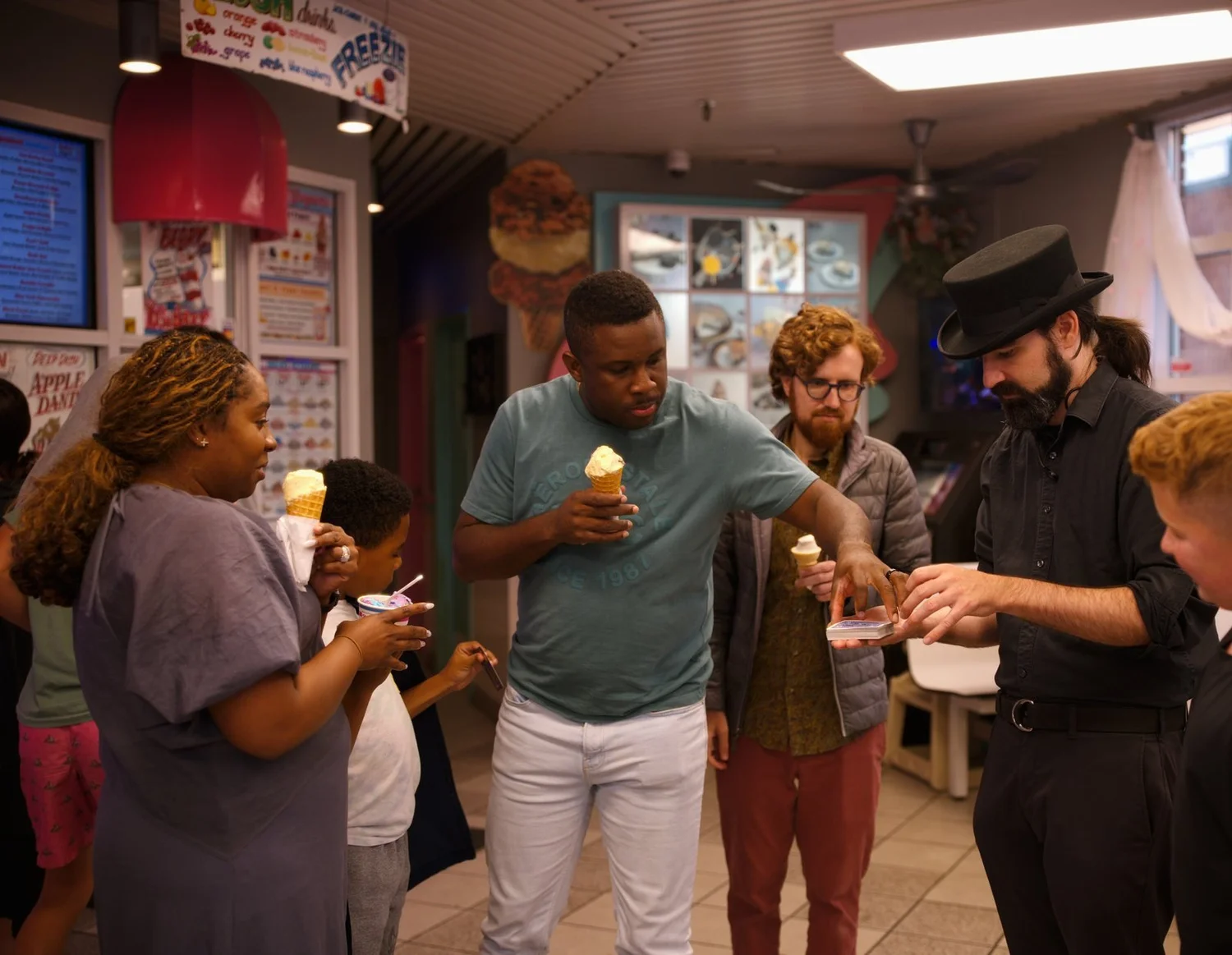 Guests with soft-serve cones gathered around the magician for a card trick at Merla-Mae Ice Cream in London, Ontario