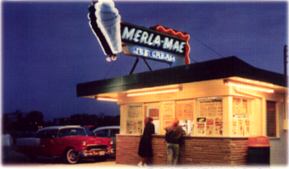 Vintage night photo of the Merla-Mae Ice Cream stand with its neon cone sign and a classic red car parked out front