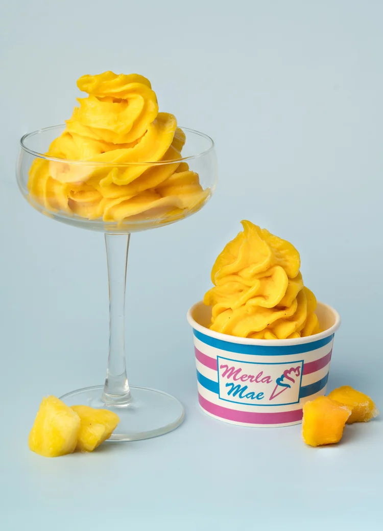 Golden-yellow mango pressed fruit in a glass dish and a striped cup, with fresh fruit pieces, at Merla-Mae Ice Cream in London, Ontario