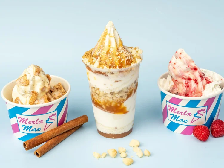 Two loaded soft-serve sundaes in striped Merla-Mae cups beside a layered parfait at Merla-Mae Ice Cream in London, Ontario